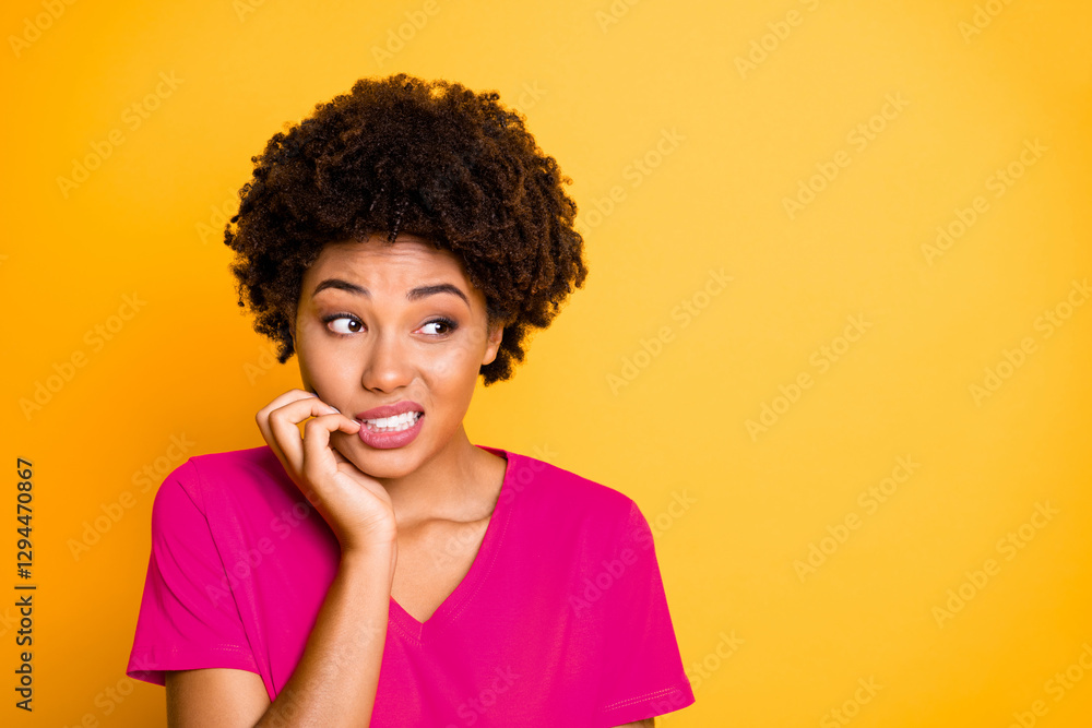 Copyspace photo of frightened afraid fearful woman biting her nails while observing terrible stuff going on wearing orange t-shirt isolated over yellow vivid color background Copyspace photo of frightened afraid fearful woman biting her nails while observing terrible stuff going on wearing orange t-shirt isolated over yellow vivid color background