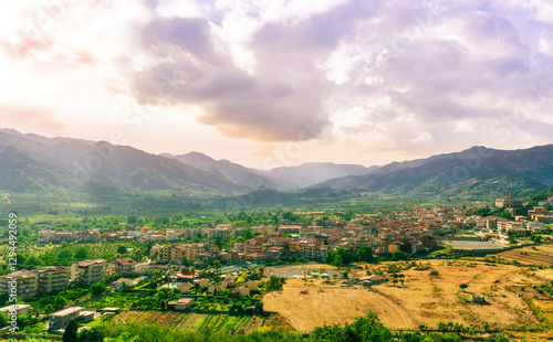 beautiful evening or morning landscape of amazing small mountain town in highland walley with houses and orange roofs and nice sunset cloudy sky with mountains on background