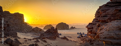 A group of 4x4 campers set up camp among the rock formations that jut out of the sand of Tadrart Rouge, in the heart of the Algerian Sahara desert.