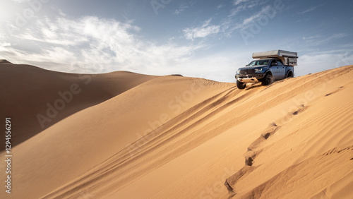 A 4x4 camper  crosses a sand dune of the Admer erg in the heart of the Algerian Sahara desert