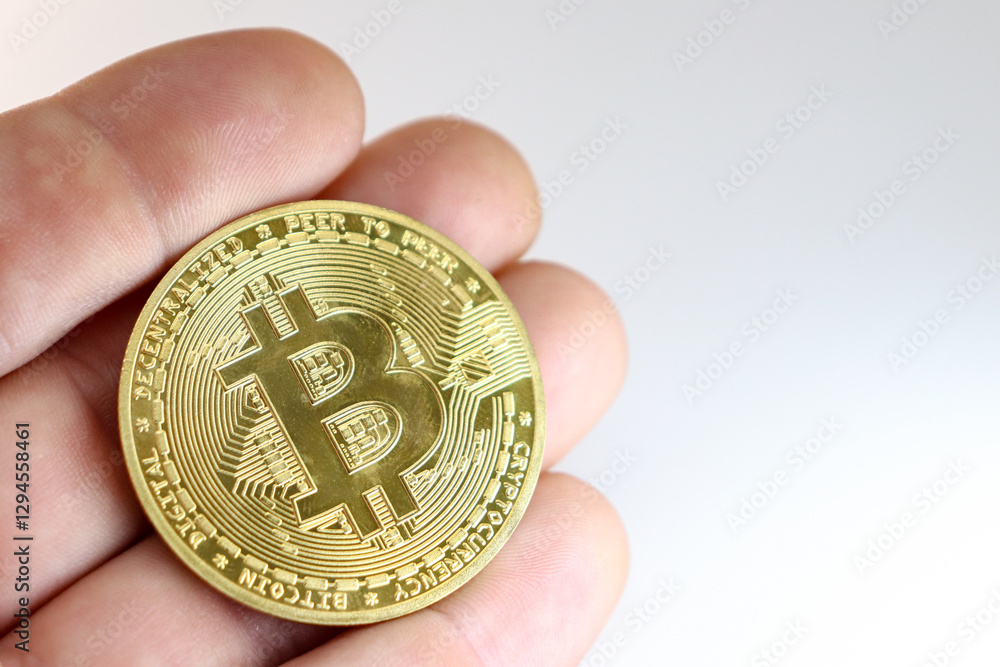 Hand holding a gold color bitcoin coin on white background with copy space. Concept of financial asset acquisition, devaluation of digital money. Hand holding a gold color bitcoin coin on white background with copy space. Concept of financial asset acquisition, devaluation of digital money.