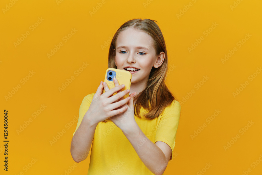 Happy young girl smiling while taking a selfie with a smartphone against a bright yellow background, wearing a cheerful yellow shirt, showcasing joy and youthfulness Happy young girl smiling while taking a selfie with a smartphone against a bright yellow background, wearing a cheerful yellow shirt, showcasing joy and youthfulness