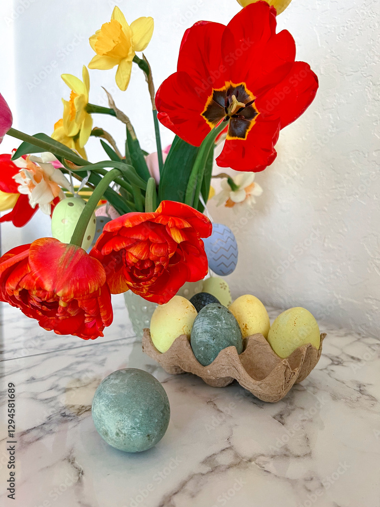Bright colorful eggs are packed on the table next to a bouquet of tulips. An Easter card. Close. Vertical photography