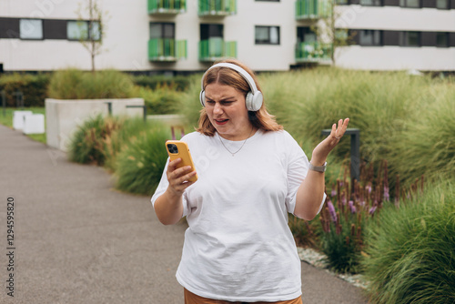 Upset sad, skeptical, serious woman holding smartphone gadget for communicate outdoors. Negative people emotion, Urban lifestyle concept. Angry 30s girl reading bad news