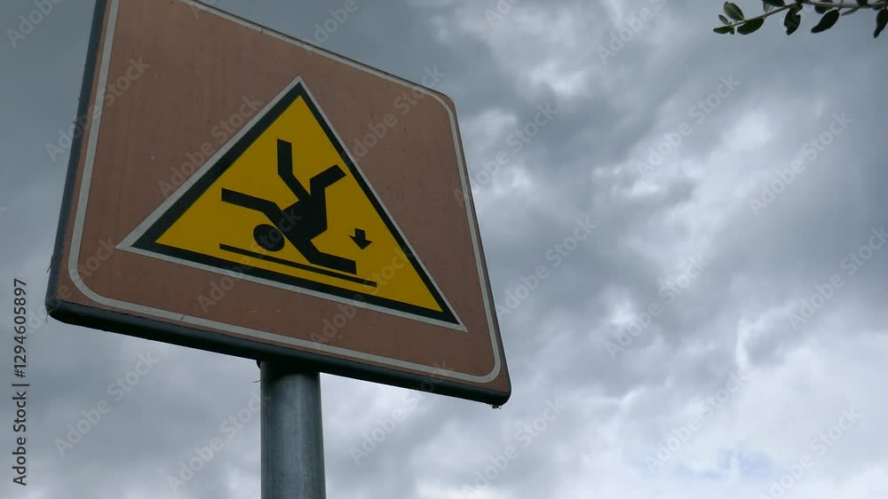 Risk of slipping and falling warning sign with clouds in sky background Risk of slipping and falling warning sign with clouds in sky background