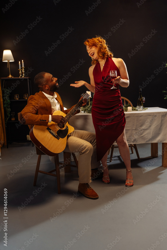 Fototapeta premium Musician playing acoustic guitar for elegant woman during romantic dinner