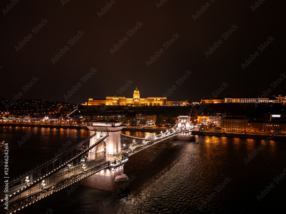 Fototapeta premium Széchenyi Chain Bridge connecting Buda and Pest at night with Buda Castle illuminated Aerial view