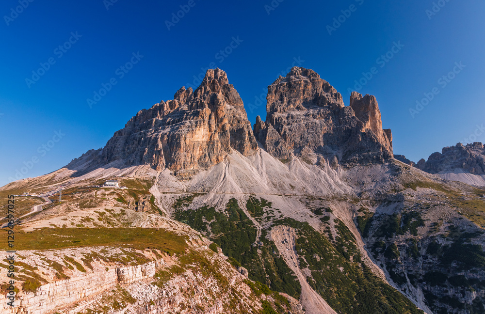 Tre Cime di Lavaredo during sunrise with warm golden light with a person in the foreground