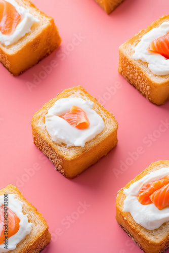Mini sandwiches with salmon and cream on pink background