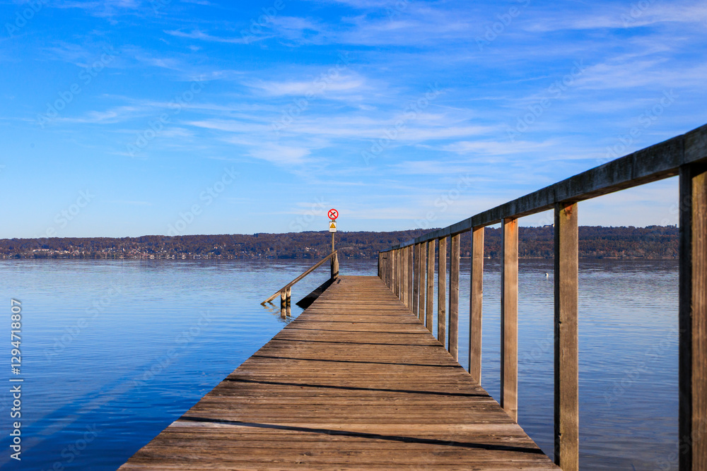 Wooden pier extending over calm lake with warning sign, Ammersee, Germany, Riederau, 01.11.2024.. Wooden pier extending over calm lake with warning sign, Ammersee, Germany, Riederau, 01.11.2024..