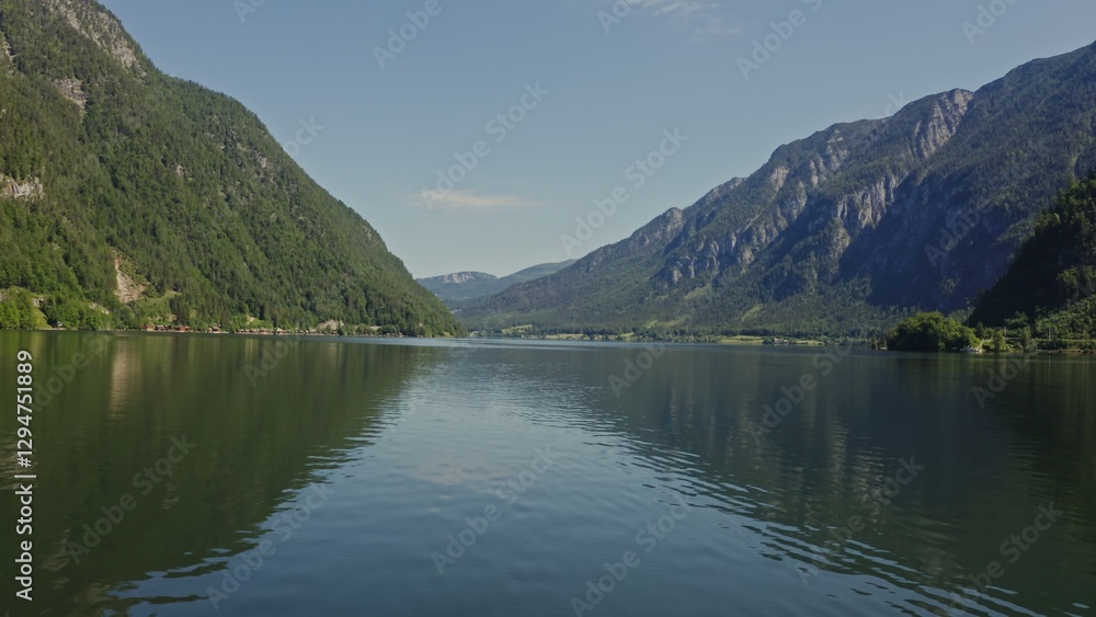 A picturesque lake located in a lowland between gently sloping mountains overgrown with a dense spruce forest. Panoramic video from a drone on a summer sunny day. Austria A picturesque lake located in a lowland between gently sloping mountains overgrown with a dense spruce forest. Panoramic video from a drone on a summer sunny day. Austria