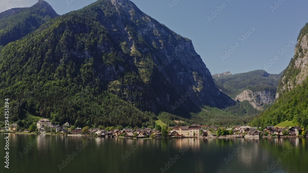 Fototapeta premium Non-white village with traditional houses, located on the shore of a picturesque lake, in a lowland between the Alps. Austria, Hallstatt, drone video