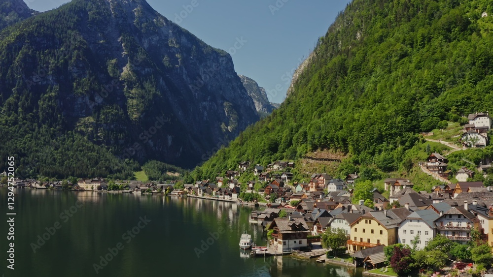 Naklejka premium A small Austrian town located on the coast of a picturesque lake at the foot of green mountains. Austria, Hallstatt, drone video