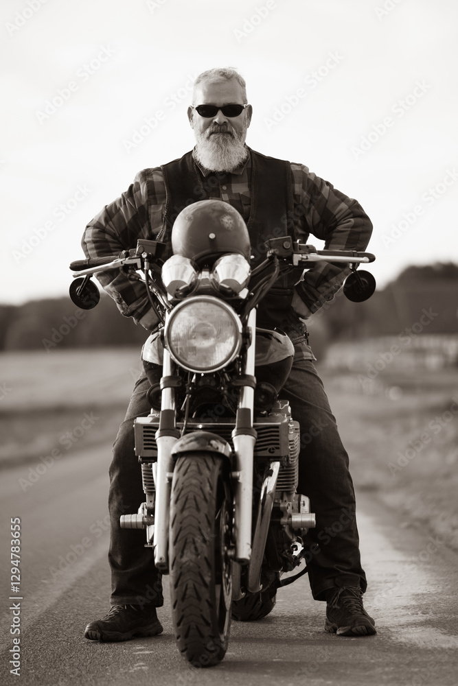 Naklejka premium Cooler Motorradfahrer sitzt startbereit auf seinem Motorrad - Frontansicht im Hochformat.