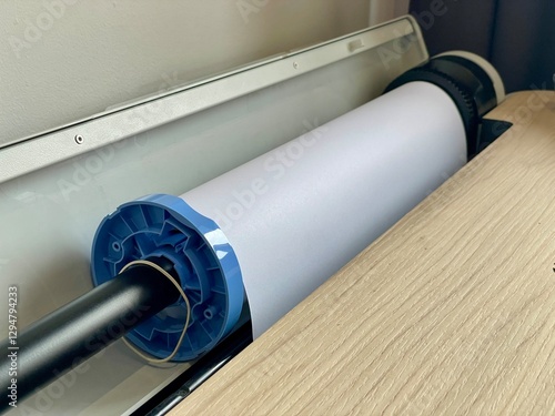 Paper roll installed in a plotter printer, with a visible mounting mechanism
