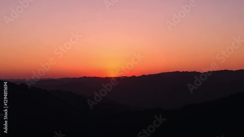 Wallpaper Mural A beautiful sunset over rolling hills with a deep orange sky, creating a peaceful evening scene. Torontodigital.ca