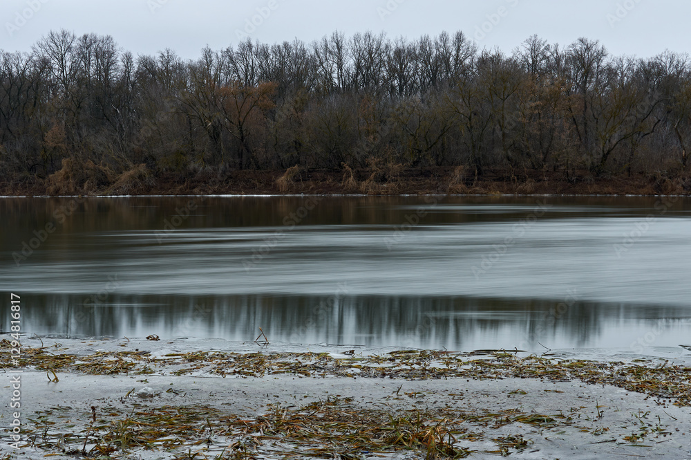 Long exposure photo of the river, late autumn, the trees on the shore are bare, the sky is cloudy, a beautiful autumn landscape Long exposure photo of the river, late autumn, the trees on the shore are bare, the sky is cloudy, a beautiful autumn landscape