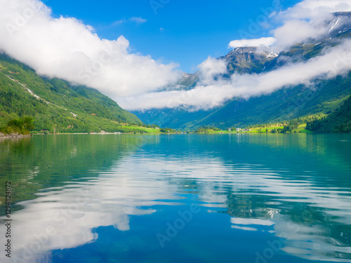 Mountain lake in Norway. Nature in fjords. High mountains and reflections on the surface of the water. Clouds over the rocks. Vacation and travel in summer Norway. photo