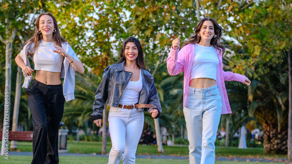 Three young female friends running and having fun together in a grassy park on a summer day Three young female friends running and having fun together in a grassy park on a summer day