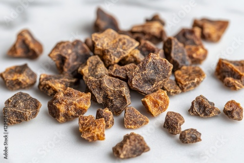 Scattered pieces of dried propolis on a light surface, showcasing their irregular shapes and rich brown hues