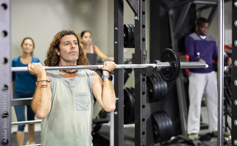 Caucasian man training with barbell using squat rack in gym Caucasian man training with barbell using squat rack in gym