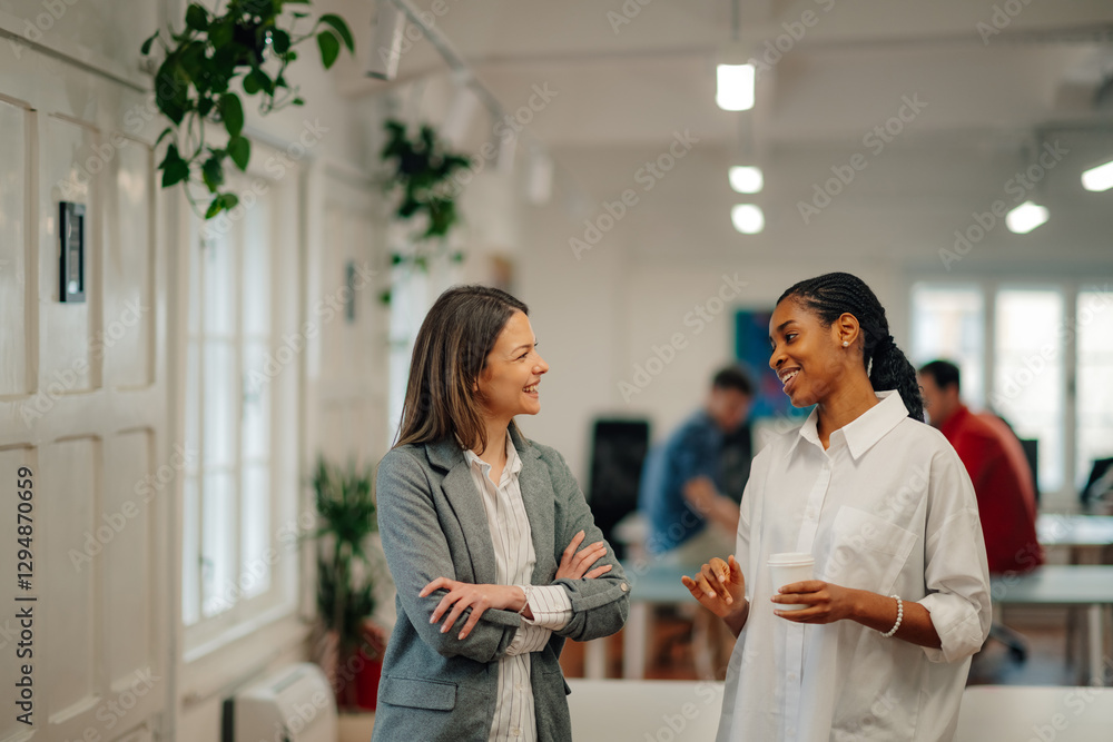 Fototapeta premium Two businesswomen talking during coffee break in modern office