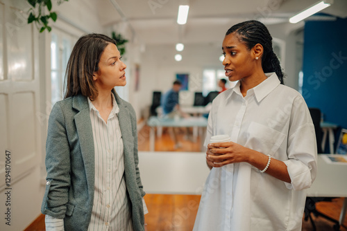 Two businesswomen talking seriously during coffee break in office