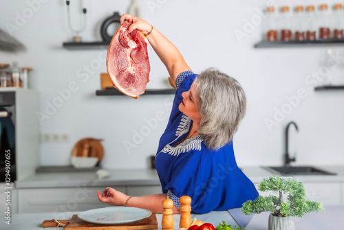 Beautiful woman holding a piece of fresh juicy meat tenderloin while cooking in the kitchen. Healthy and organic eating. Vitamin foods are good for your health.