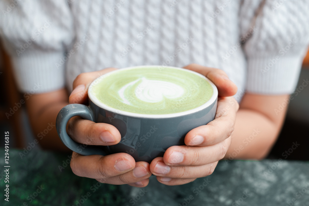 Warm hands cradle a matcha latte with heart foam art, creating a cozy and inviting atmosphere. Warm hands cradle a matcha latte with heart foam art, creating a cozy and inviting atmosphere.