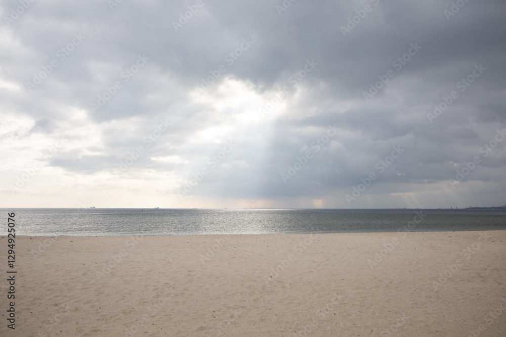 Sun shining through clouds on empty beach by the Baltic sea Sun shining through clouds on empty beach by the Baltic sea
