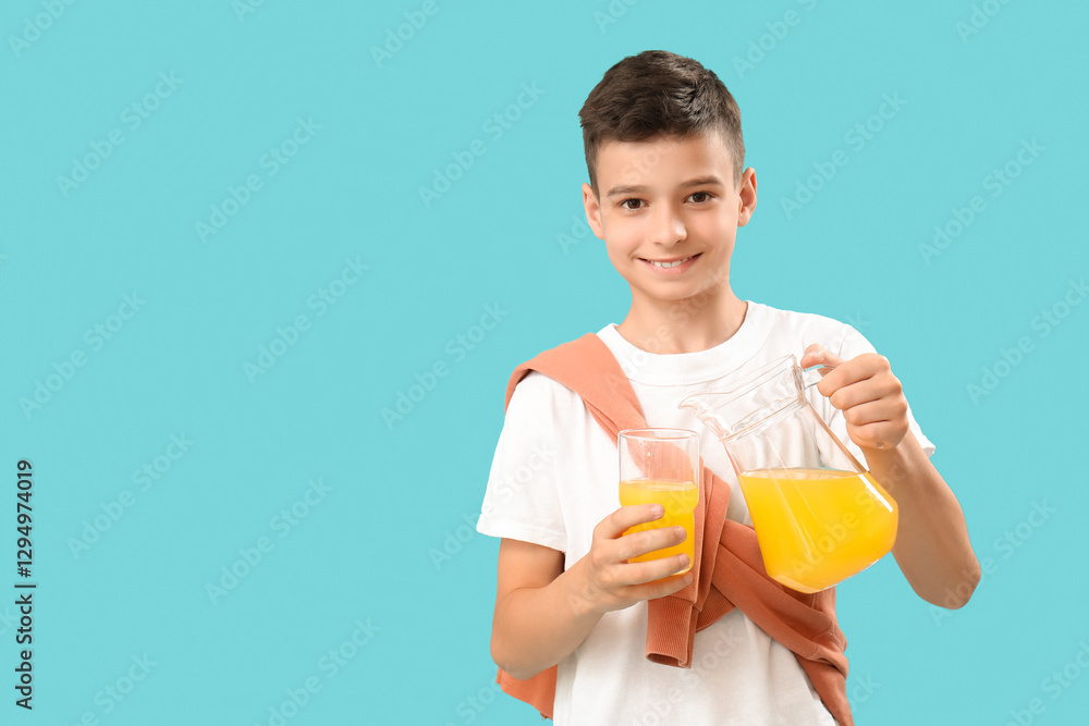 Little boy pouring orange juice into glass on blue background Little boy pouring orange juice into glass on blue background