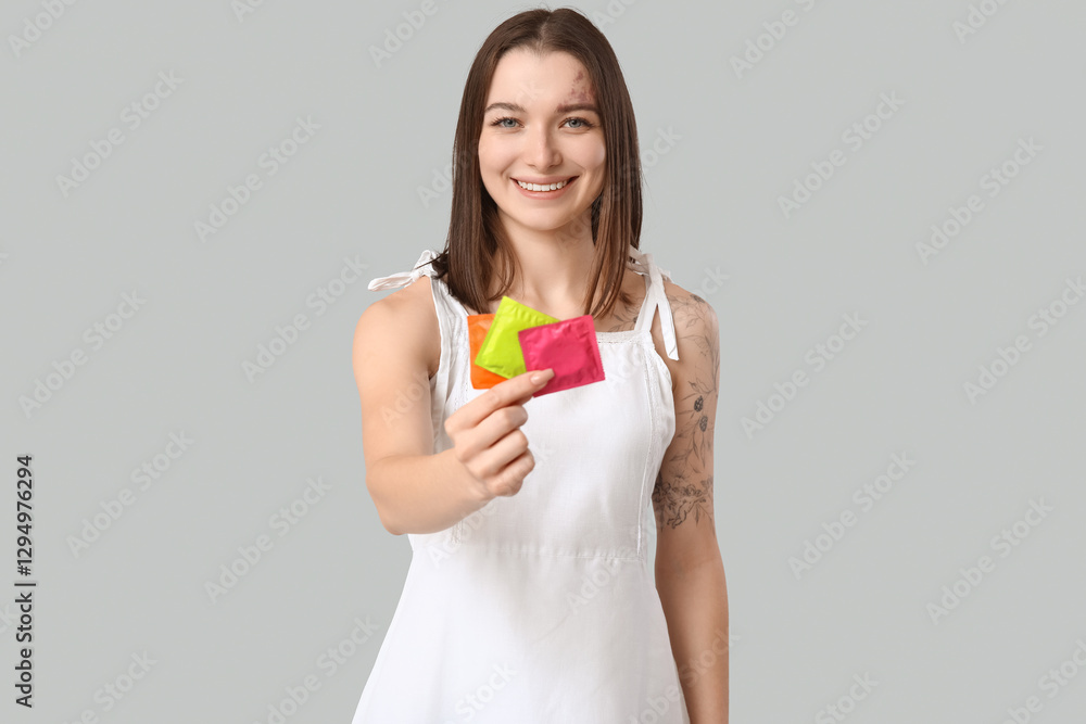 Beautiful young woman with condoms on grey background. AID awareness concept Beautiful young woman with condoms on grey background. AID awareness concept
