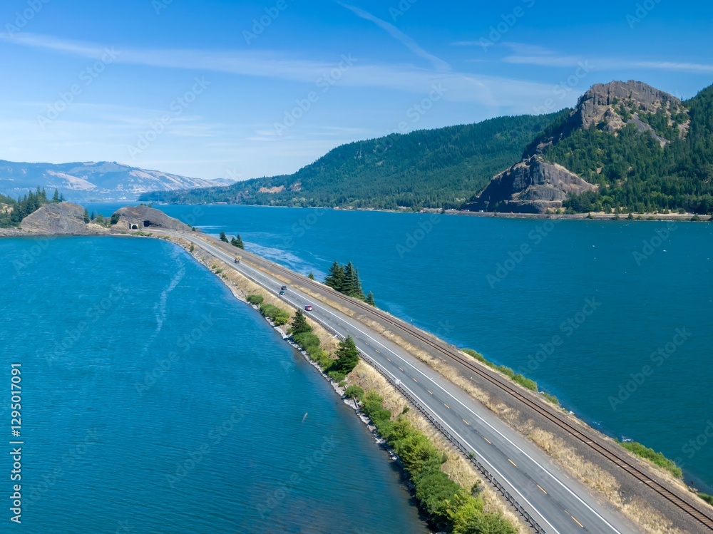 Highway and train tracks alongside a scenic Columbia River. Cars travel along the road, showcasing the beauty of the Columbia River Gorge. ,Drano, Washington, USA Highway and train tracks alongside a scenic Columbia River. Cars travel along the road, showcasing the beauty of the Columbia River Gorge. ,Drano, Washington, USA