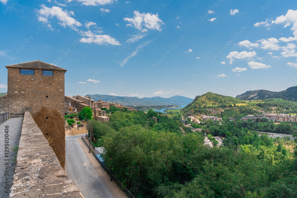 Naklejka premium Paisaje urbano de un pueblo medieval en los pirineos, un día soleado con cielo azul y nubes. Desde Ainsa, Huesca, Aragón, España, Europa.
