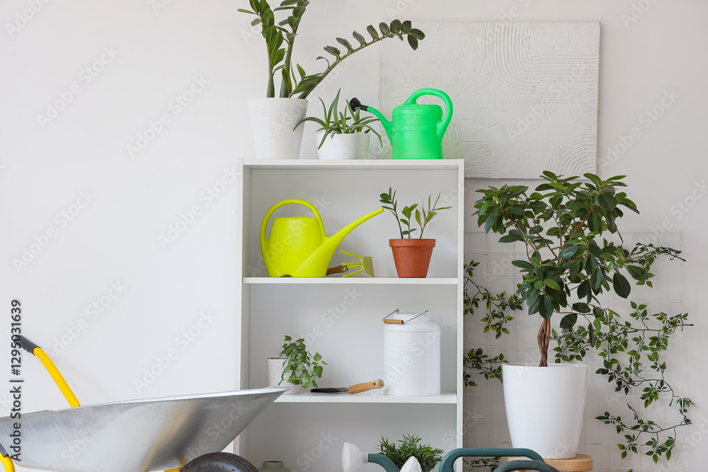 Obraz premium Set of gardening tools and plants near light wall