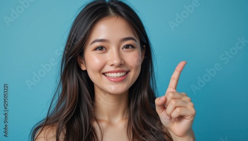 Wallpaper Mural Smiling Woman Pointing Up,  Happy Asian Female, Blue Background Studio Portrait Torontodigital.ca