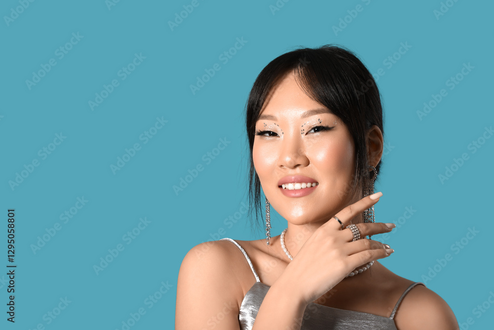 Beautiful Asian woman in silver jewellery on blue background Beautiful Asian woman in silver jewellery on blue background