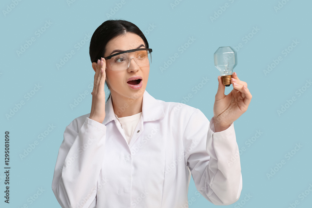Shocked female inventor with light bulb on blue background Shocked female inventor with light bulb on blue background
