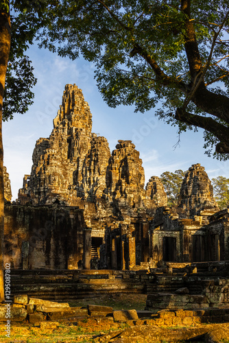 Wallpaper Mural Evening Glow.  Bayon Temple, Angkor, Cambodia glows orange in the early evening sun.  Trees form a frame in the foreground. Torontodigital.ca