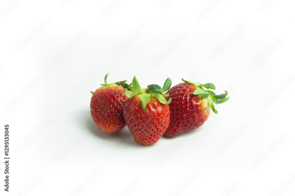 strawberries are arranged in a heart shape on a white background. The berries are red with green stems, some showing a transition to lighter, unripe areas. The image is a top-down view strawberries are arranged in a heart shape on a white background. The berries are red with green stems, some showing a transition to lighter, unripe areas. The image is a top-down view