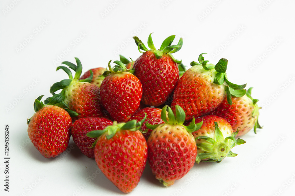 strawberries are arranged in a heart shape on a white background. The berries are red with green stems, some showing a transition to lighter, unripe areas. The image is a top-down view strawberries are arranged in a heart shape on a white background. The berries are red with green stems, some showing a transition to lighter, unripe areas. The image is a top-down view