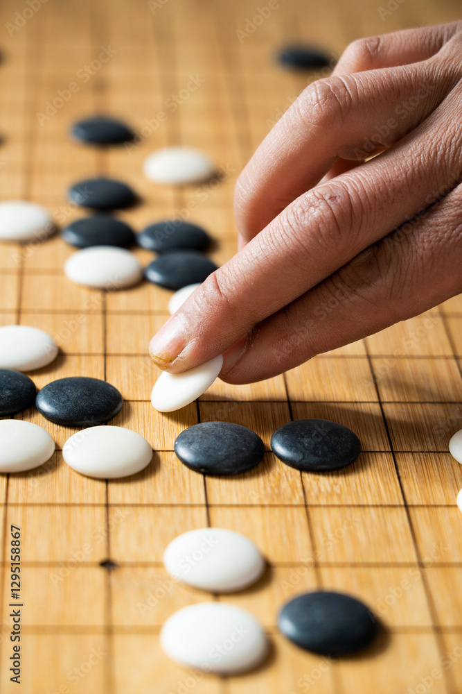 close up of player hand make a move in Go game(Weiqi),Traditional trategy board game close up of player hand make a move in Go game(Weiqi),Traditional trategy board game