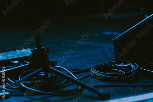 Amps Cords and Mic Stands on a Dark Lit Stage
