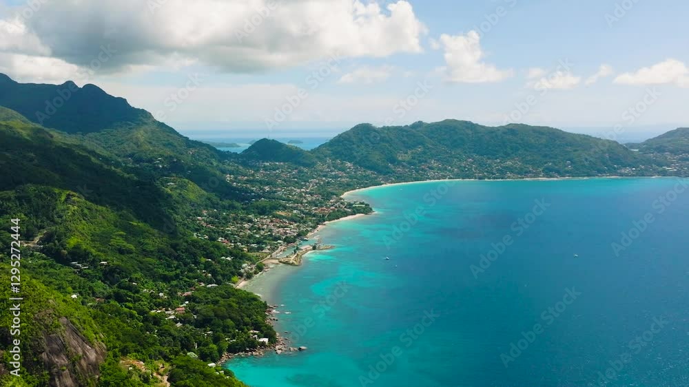 A coastal landscape with blue ocean waters meeting the green hills, dotted with small settlements along the shoreline. Seychelles, Mahe. A coastal landscape with blue ocean waters meeting the green hills, dotted with small settlements along the shoreline. Seychelles, Mahe.