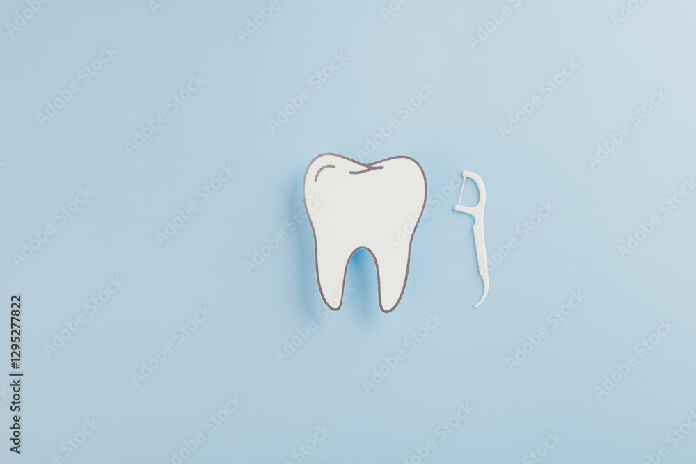 Dentist Day concept. A paper tooth model and floss on a blue background Dentist Day concept. A paper tooth model and floss on a blue background