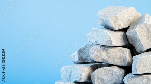 A stack of gray stones against a soft blue background, ideal for construction or design themes photo