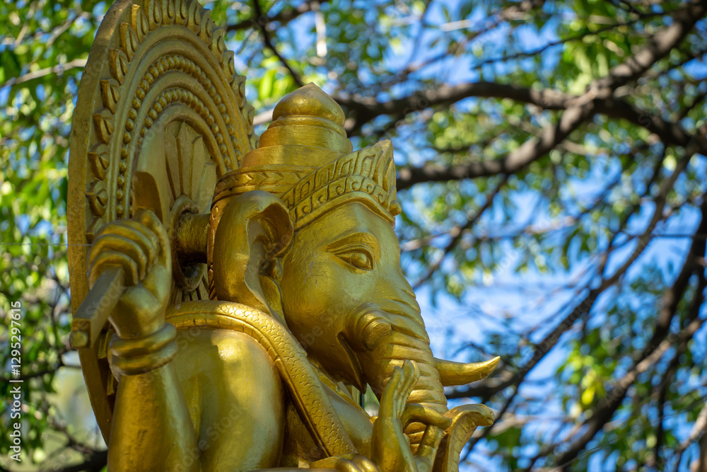 Golden Statue of Lord Ganesha Surrounded by Green Foliage Golden Statue of Lord Ganesha Surrounded by Green Foliage