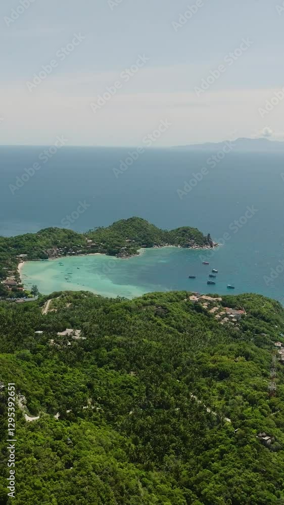 Island coastline with a turquoise bay, dense greenery, and small scattered boats under a sunny sky. Koh Tao, Thailand. Island coastline with a turquoise bay, dense greenery, and small scattered boats under a sunny sky. Koh Tao, Thailand.