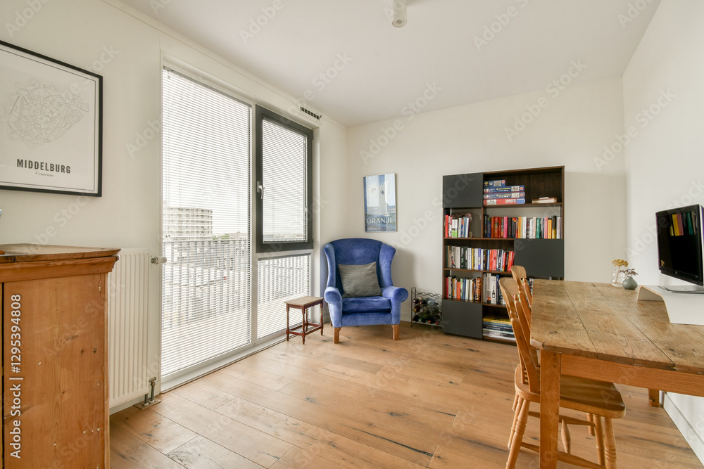 Fototapeta premium Bright and airy room featuring a blue chair, wooden flooring, and a bookshelf filled with books, creating a cozy reading nook.