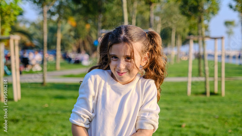 Canvas Print A little girl child standing in a wooded park on a spring day, looking at the ca